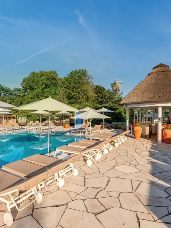 Ein Außenpool mit Liegestühlen und Sonnenschirmen.