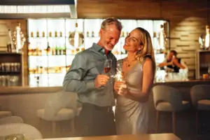 Silvester im Ifen Hotel Kleinwalsertal Ein Mann und eine Frau halten Gläser mit Champagner.