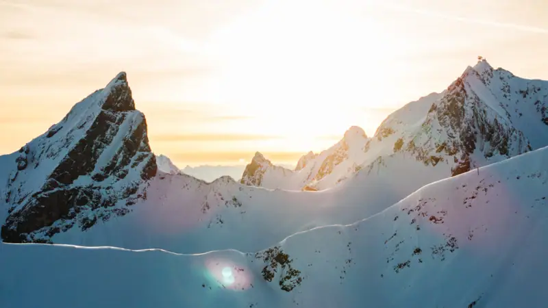 Schneebedeckte Berge mit durchscheinender Sonne.