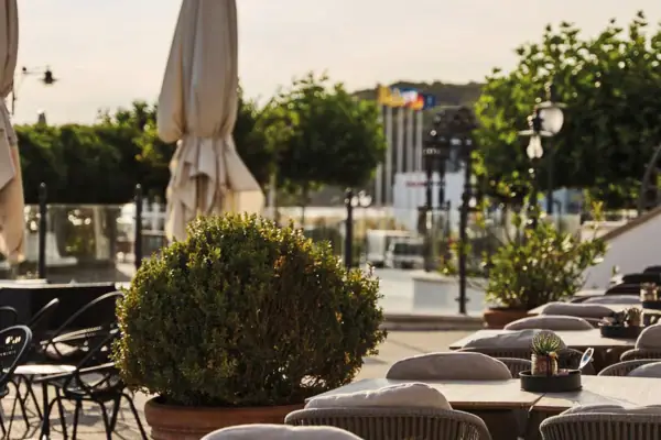 Terrasse Tische und Stühle im Freien mit Bäumen und einer Straße im Hintergrund.
