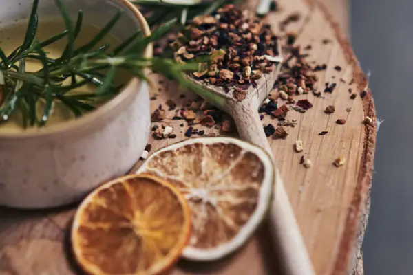 Löffel mit Gewürzen und Schale mit Flüssigkeit auf Holzoberfläche