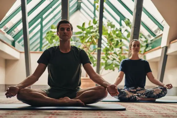 Ein Mann und eine Frau sitzen auf Yogamatten.