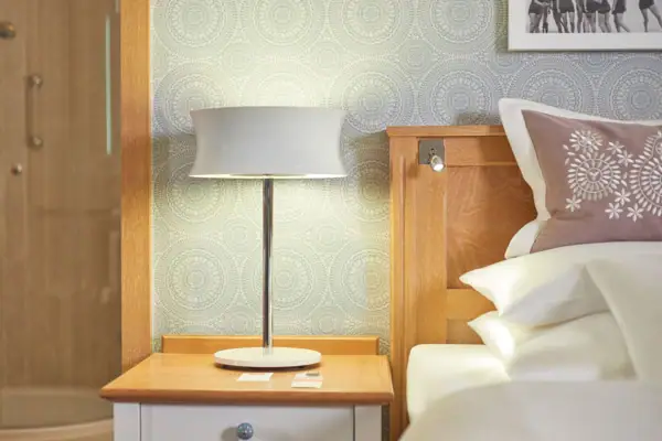 Zimmer Lampe auf einem Nachttisch neben einem Bett im Schlafzimmer.