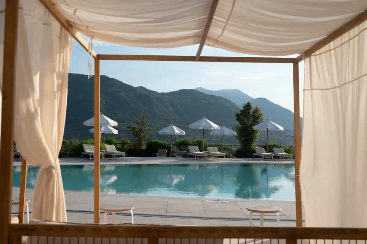 Außenpool A-ROSA Gardasee Ein Pool mit Stühlen und Sonnenschirmen im Freien.