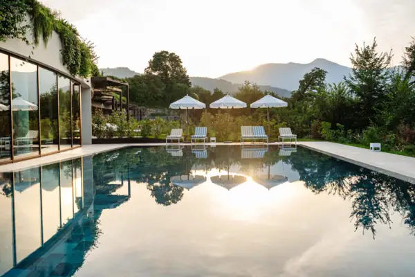 Ein Pool mit Liegestühlen und Sonnenschirmen im Hintergrund.