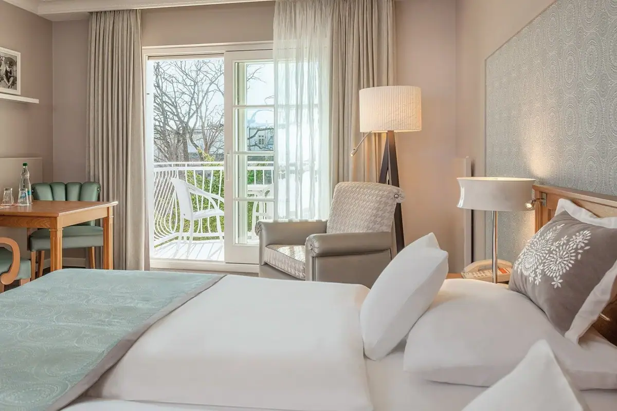 Schlafen und sich wohlfühlen. Blick auf ein Doppelbett und eine geöffnete Balkontür