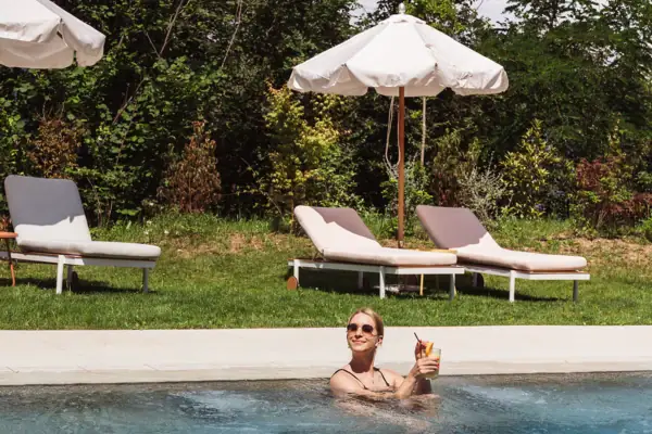 Eine Frau im Pool mit einem Getränk in der Hand.