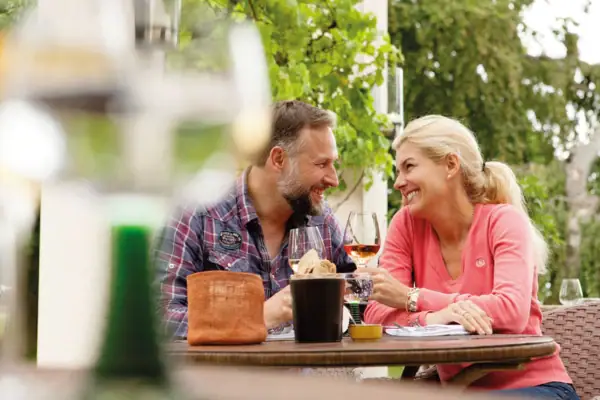 A-ROSA Travemünde Ein Mann und eine Frau sitzen an einem Tisch mit Weingläsern.