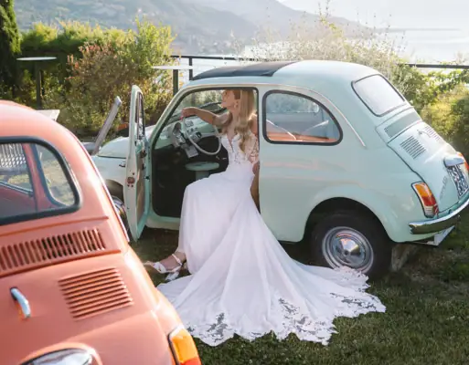 Terrasse 500 im A-ROSA Gardasee Eine Braut mit einem weißen Hochzeitskleid sitzt in einem Fiat 500.