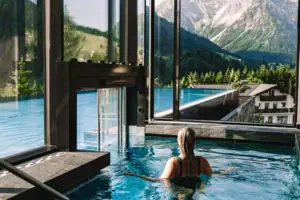 Infinitypool Eine Frau in einem Pool mit Blick auf Berge und Bäume