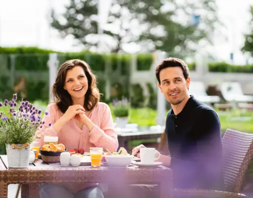 Paar im Garten Ein Mann und eine Frau sitzen an einem Tisch mit Essen.