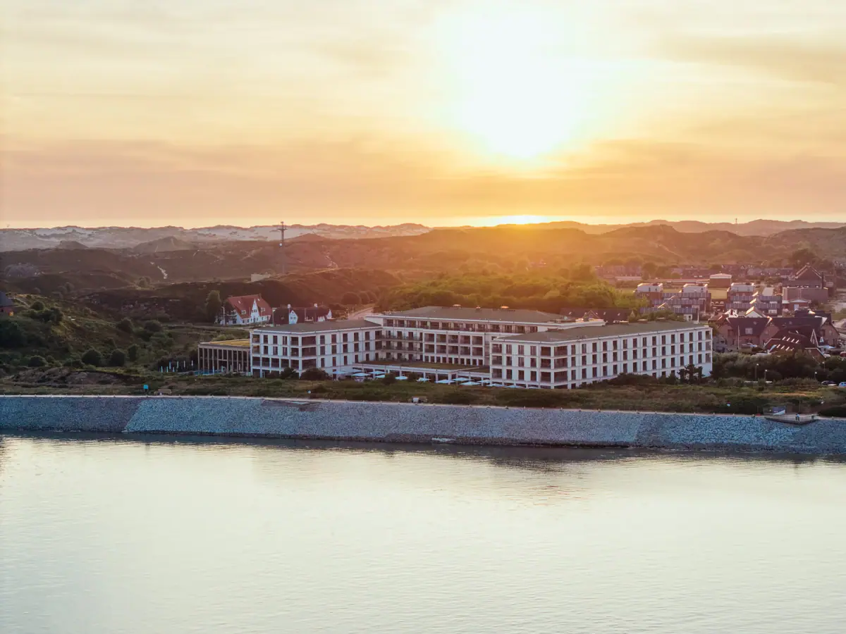 A-ROSA Sylt Hotel Ein Gebäude neben einem Gewässer im Freien bei Morgenhimmel.