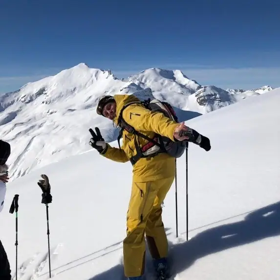 Ein Mann in einem gelben Skianzug auf einem verschneiten Berg.