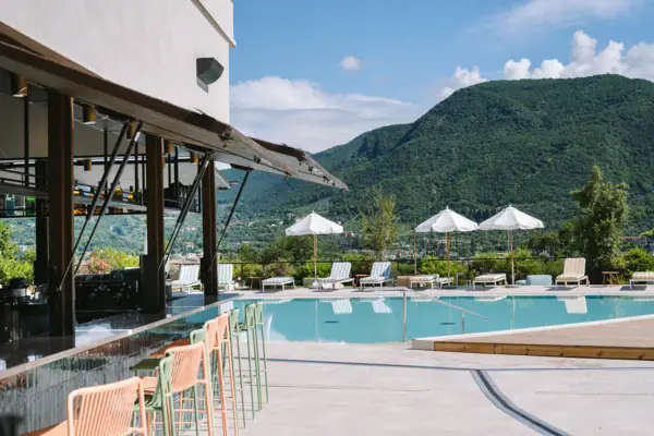 Gartenpool mit Liegen und Poolbar Ein Pool mit Liegestühlen und Sonnenschirmen neben einem Gebäude.