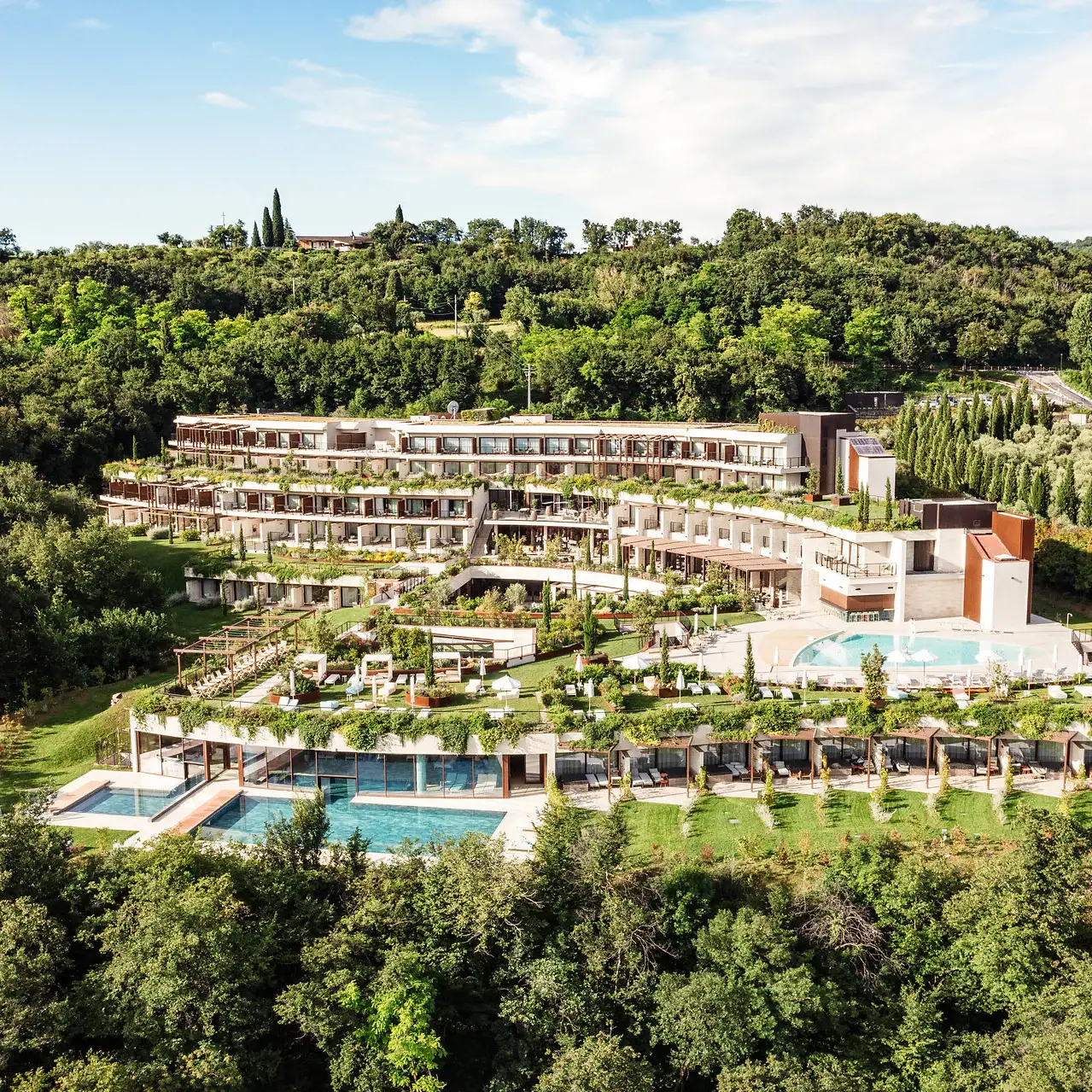 A-ROSA Gardasee Ein Gebäude mit einem Pool, umgeben von Bäumen.