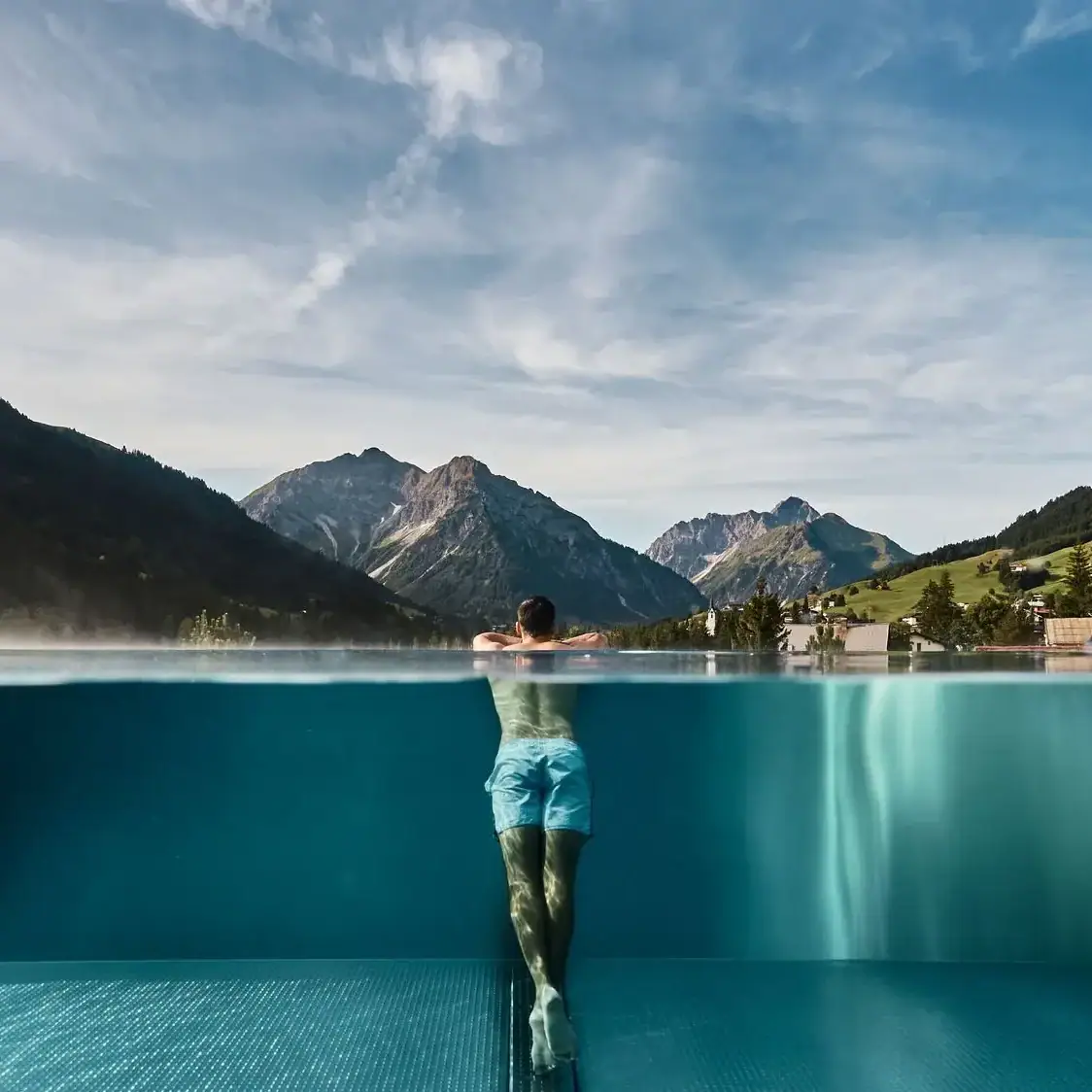 Ein Mann in einem Pool mit Bergen im Hintergrund.