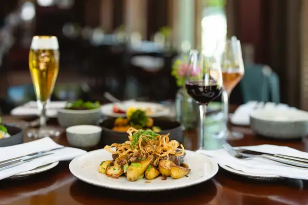 Tellerwerk Travemünde Ein Teller mit Essen auf einem Tisch, daneben ein Weinglas.