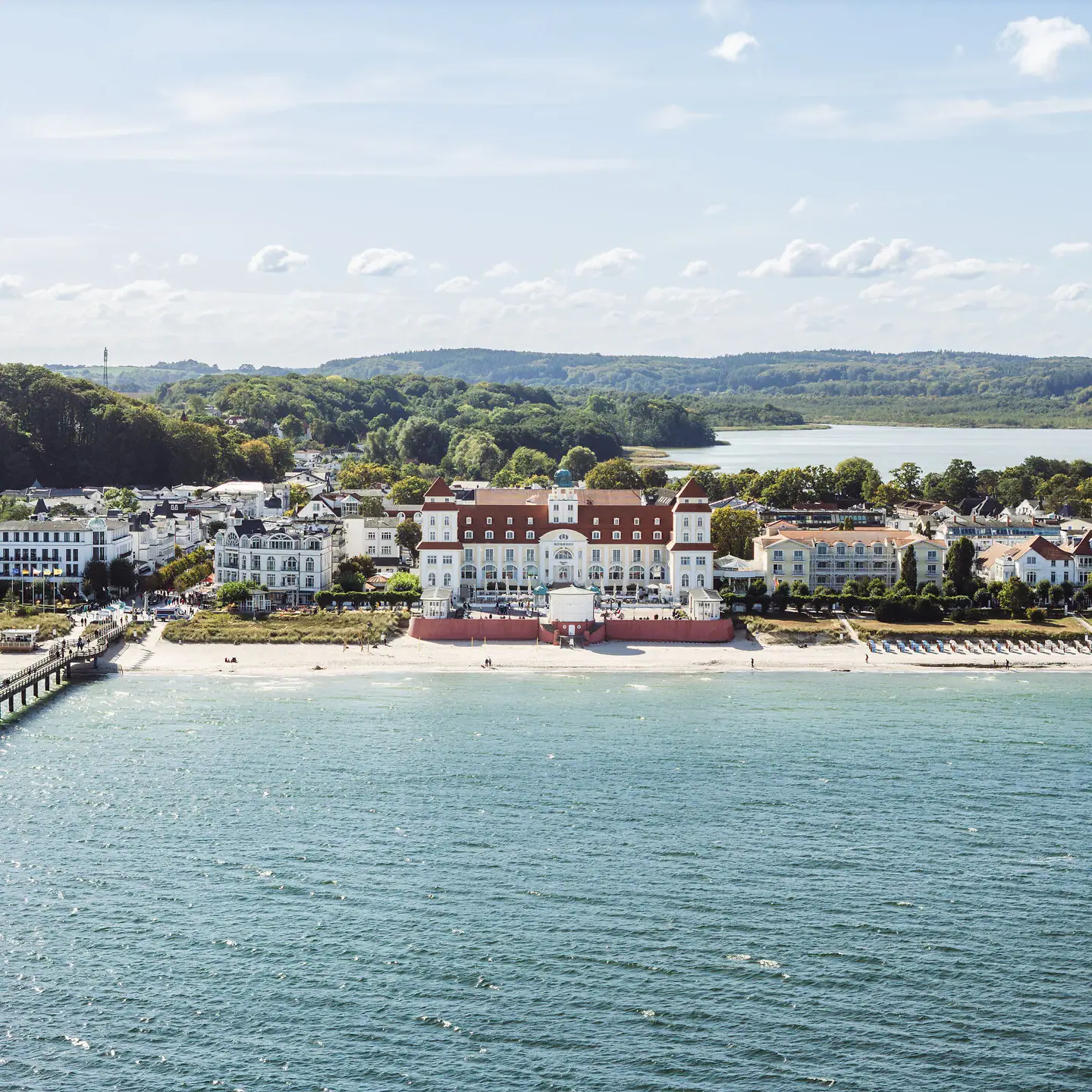 Kurhaus Binz Ein großes weißes Gebäude neben einem Gewässer.