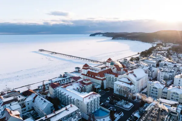 Binz im Winter Eine schneebedeckte Stadt neben einem Gewässer.