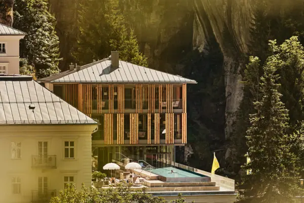 A-ROSA Bad Gastein Gebäude mit Pool in der Mitte, umgeben von Bäumen und Pflanzen.